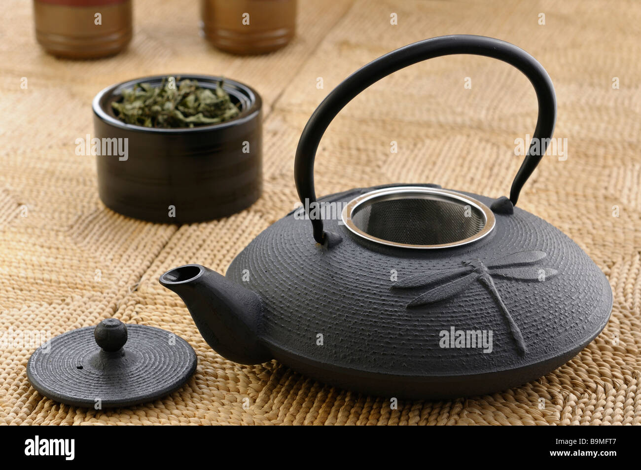 Japanese cast iron teapot with tea leaves and cups on a handmade maize mat Stock Photo