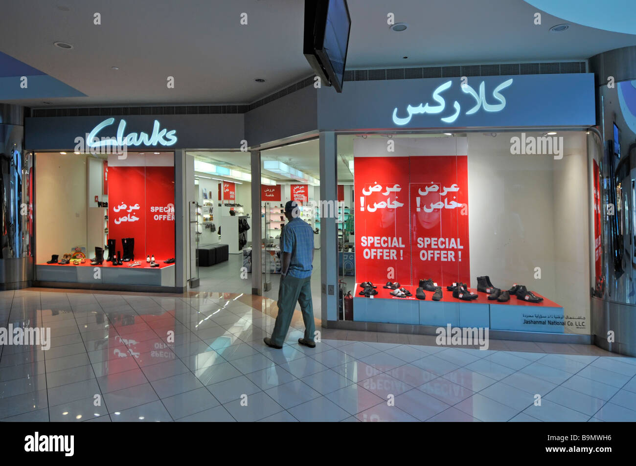 Abu Dhabi Marina shopping Mall shopper outside shoe shop retail business front window & bilingual sign special posters UAE Middle East Stock Photo - Alamy