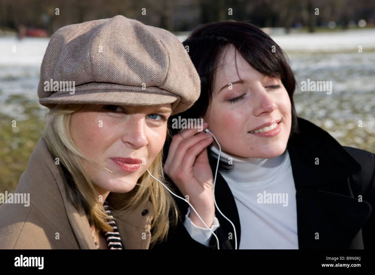 frauen hören musik über i pod auf der parkbank Stock Photo