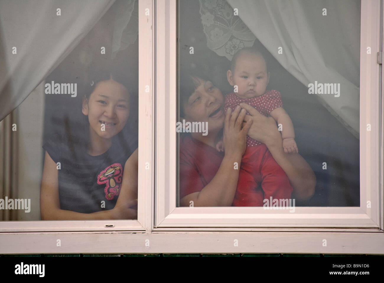 Family with baby girl looking through window, portrait, Taloyoak inuit settlement Nunavut, Canadian arctic, Canada Stock Photo