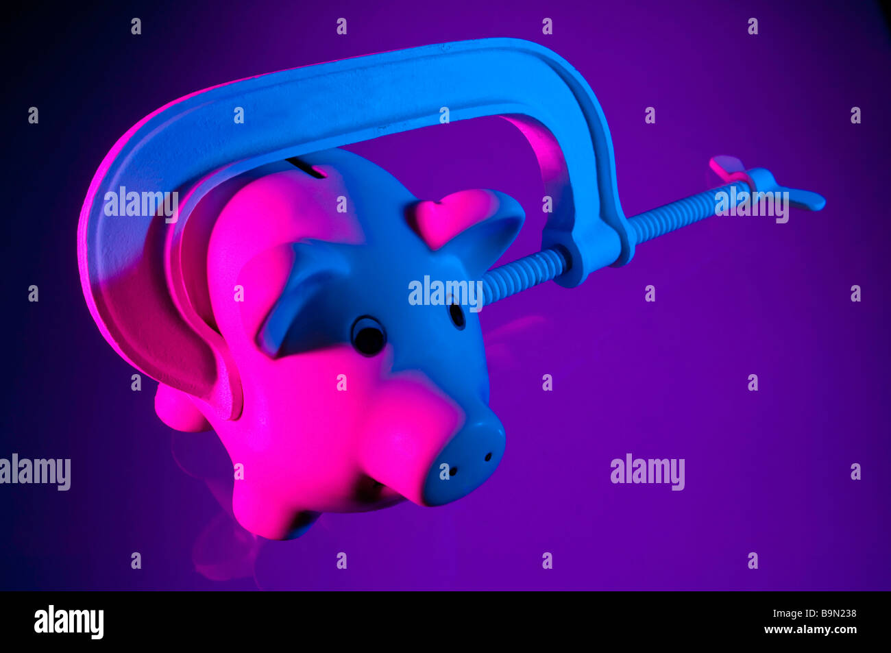 Credit squeeze concept - piggy bank in clamp. Stock Photo