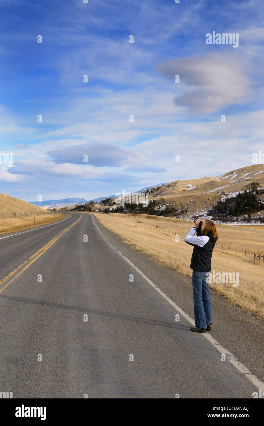 Woman tourist on Boseman Hill road at Bozeman Pass Montana USA with binoculars Stock Photo