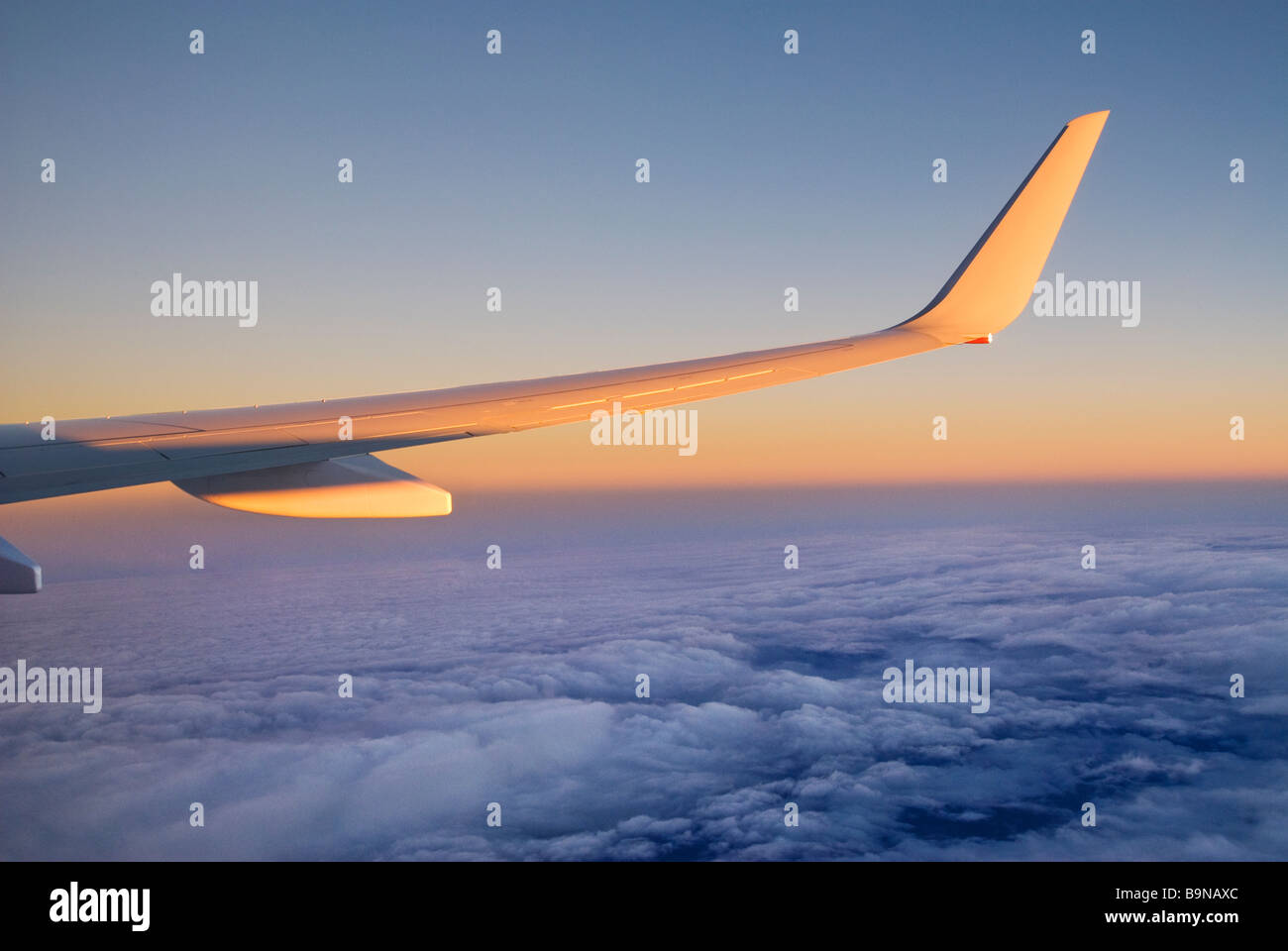View through airliner window high above clouds at sunrise Stock Photo