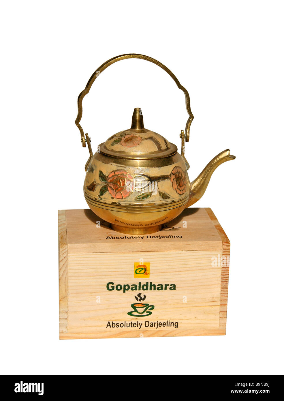 An ornate brass teapot sits on top of a box of Darjeeling tea. Stock Photo
