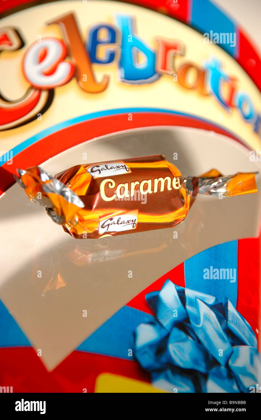 A wrapped caramel chocolate sits on an empty  chocolate box. Stock Photo