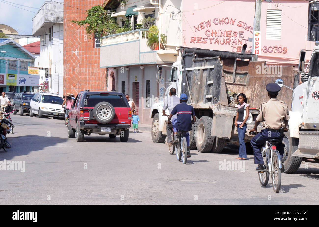 A policeman rides a bike down the crowded streets of Belize City, Central South America, a poor, impoverished tourist town. Stock Photo