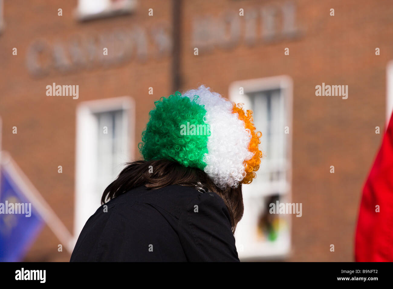 Girl in wig in colours of Irish flag watches the St Patricks Day Parade Dublin Ireland Stock Photo