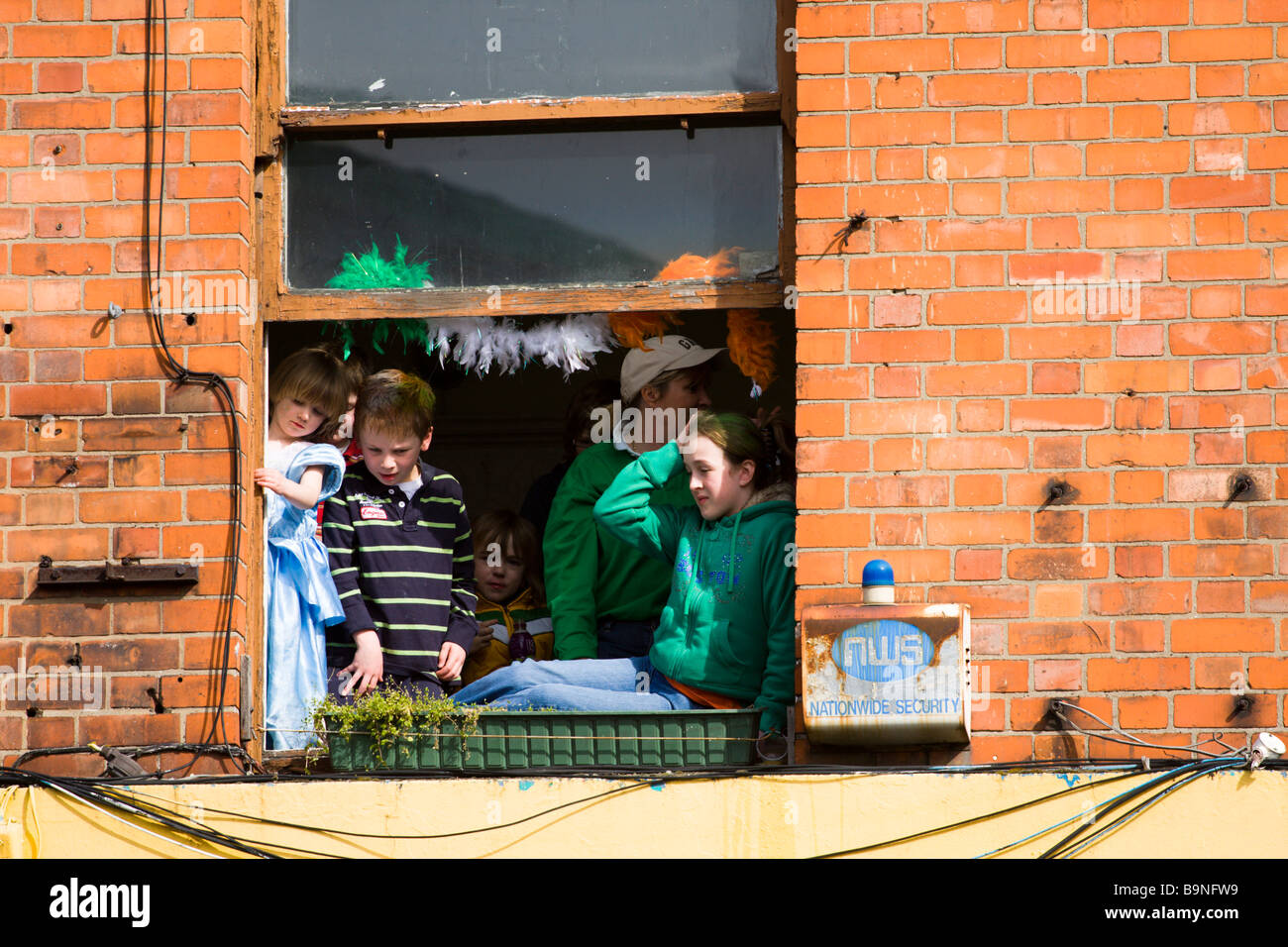 People watch the St Patrick's Day Parade Dublin from a first floor window Stock Photo