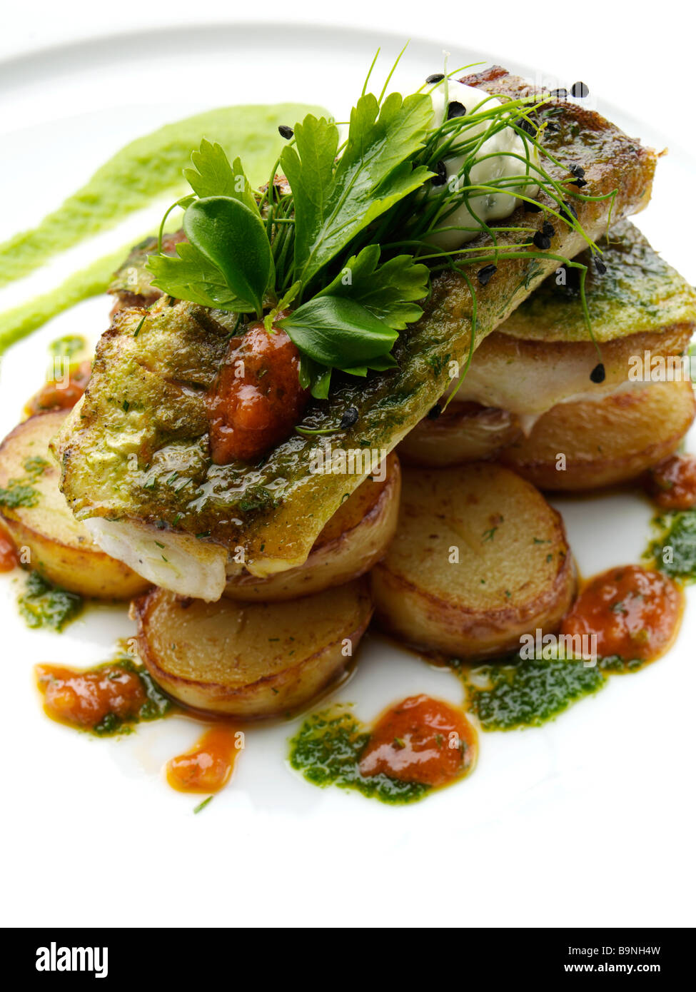 Pan fried gurnard with truffled new potato salad pea puree and salsa verde Stock Photo