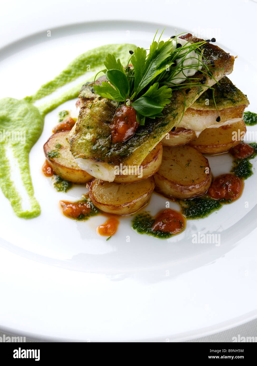 Pan fried gurnard with truffled new potato salad pea puree and salsa verde Stock Photo