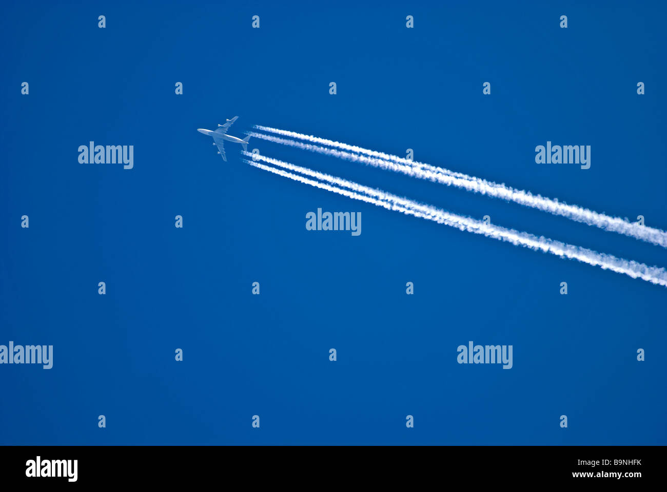 passenger jet aircraft showing contrails against a blue sky Stock Photo