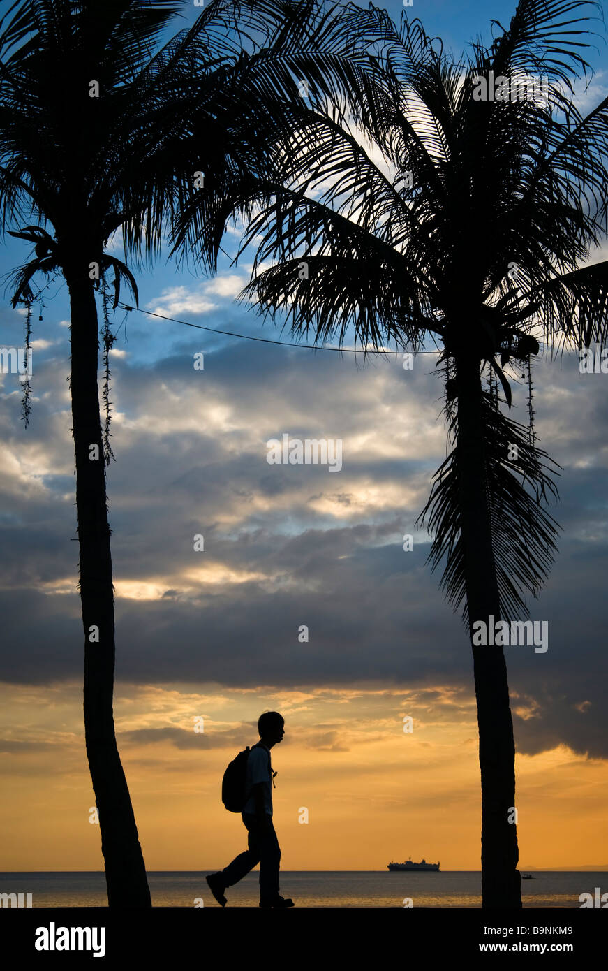 A tourist walking in the Roxas Boulevard at dusk. Stock Photo