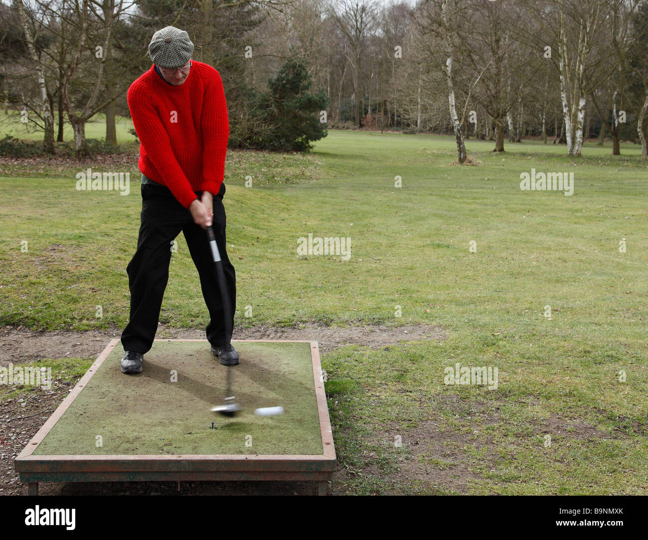 Golfer hitting a ball from a temporary tee. Stock Photo