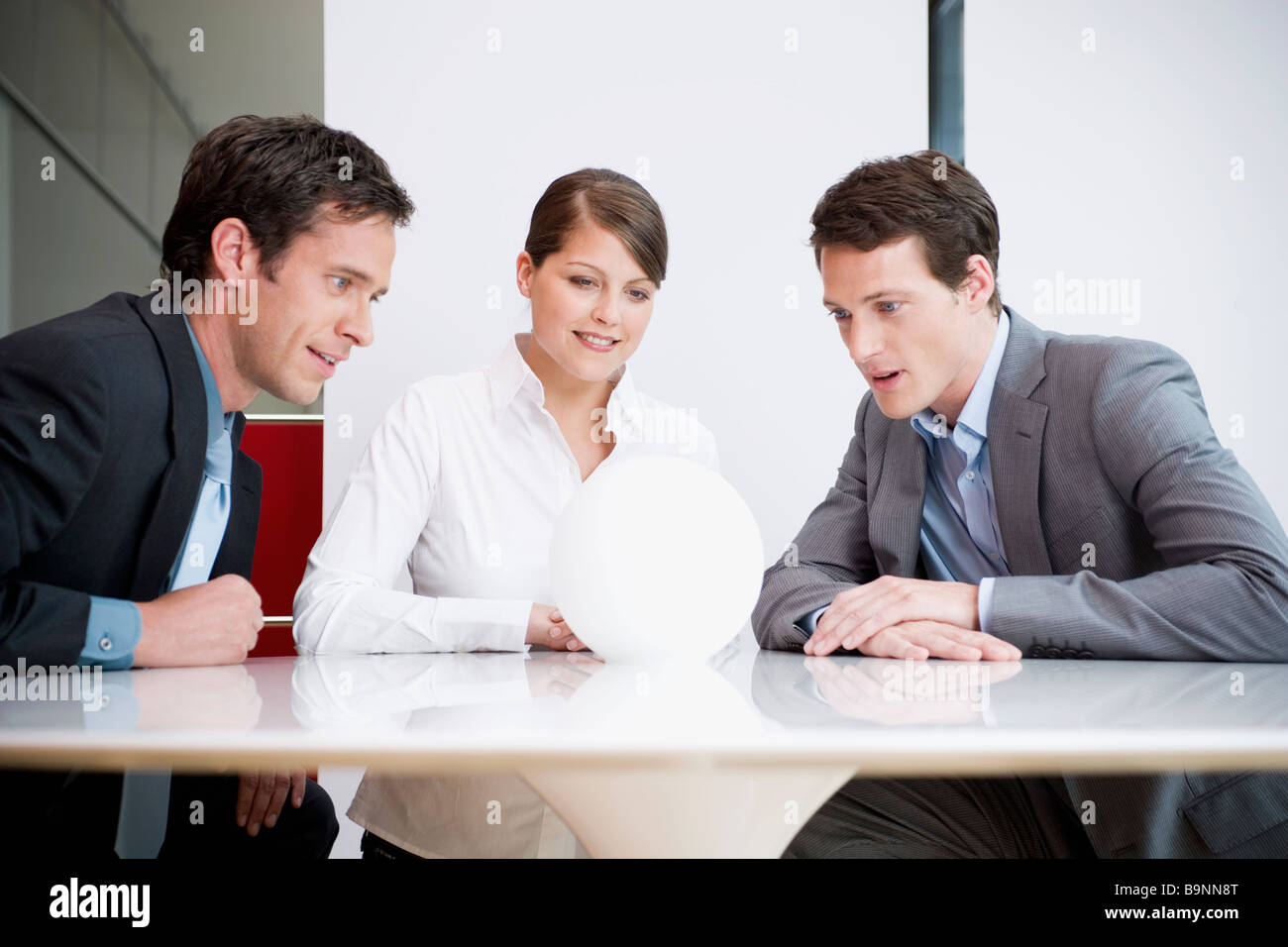 three business people sitting around table looking at crystal ball