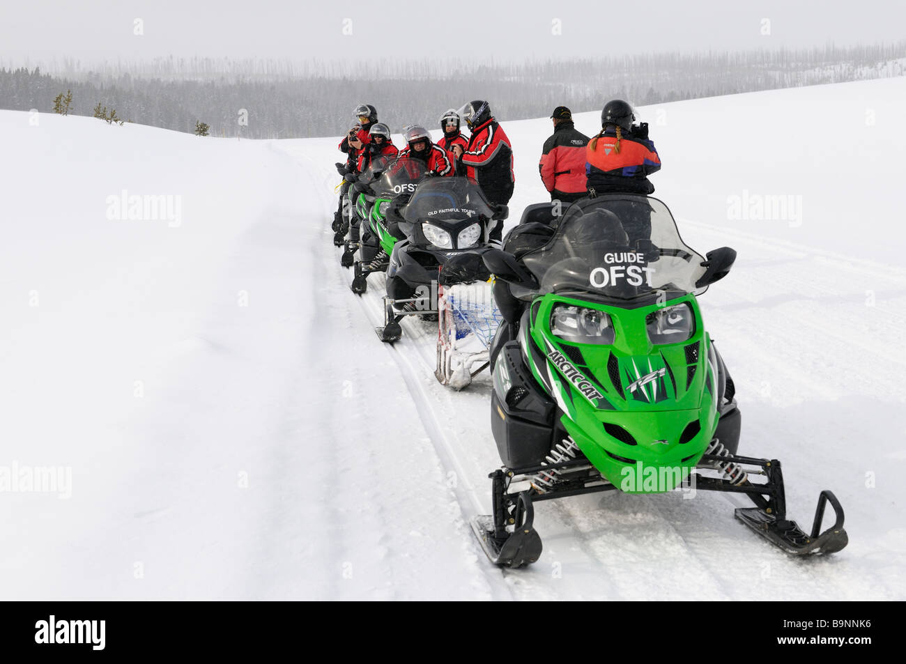 Snowmobile group stopped for pictures on Norris Canyon Road in Yellowstone National Park Wyoming USA in winter Stock Photo