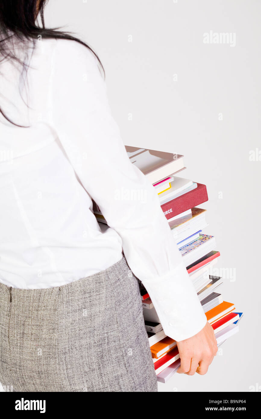 rear view of young woman carrying pile of books Stock Photo - Alamy