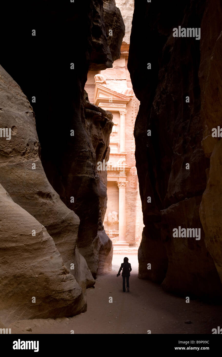 A tourist in the Siq at the entrance to Petra looking at the treasury; Petra, Jordan Stock Photo