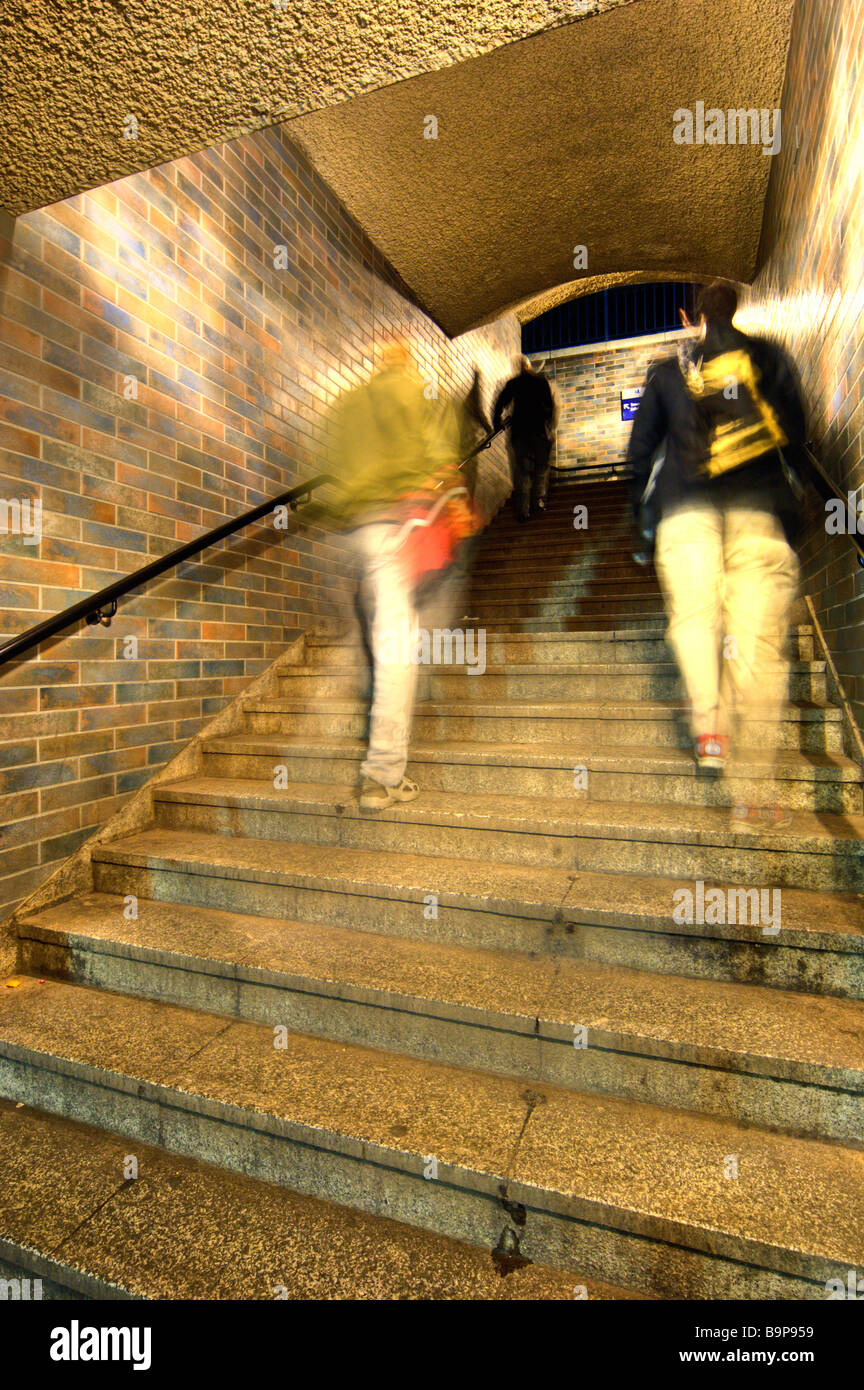 blurred moving people walking up stairs underground at night Stock Photo