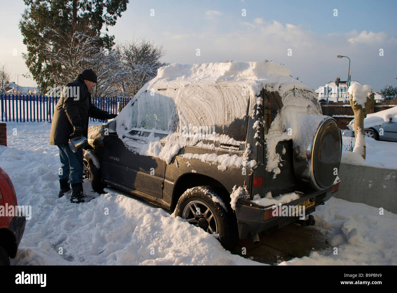 Man scraping snow from car in driveway. Stock Photo