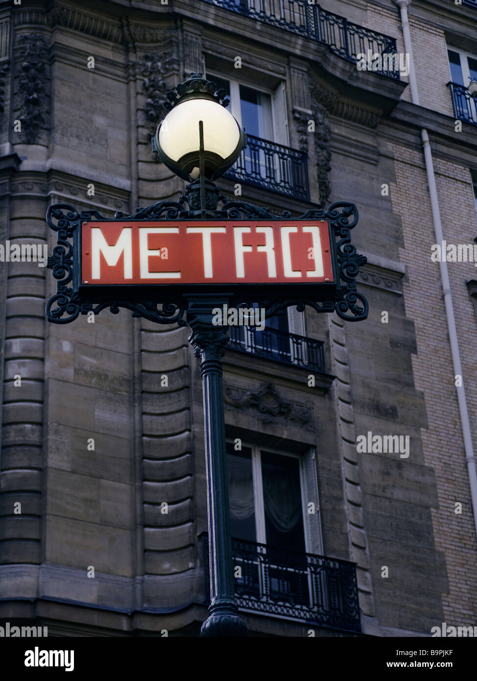 Iconic Metro underground sign at dusk with building in the background, Paris France Stock Photo