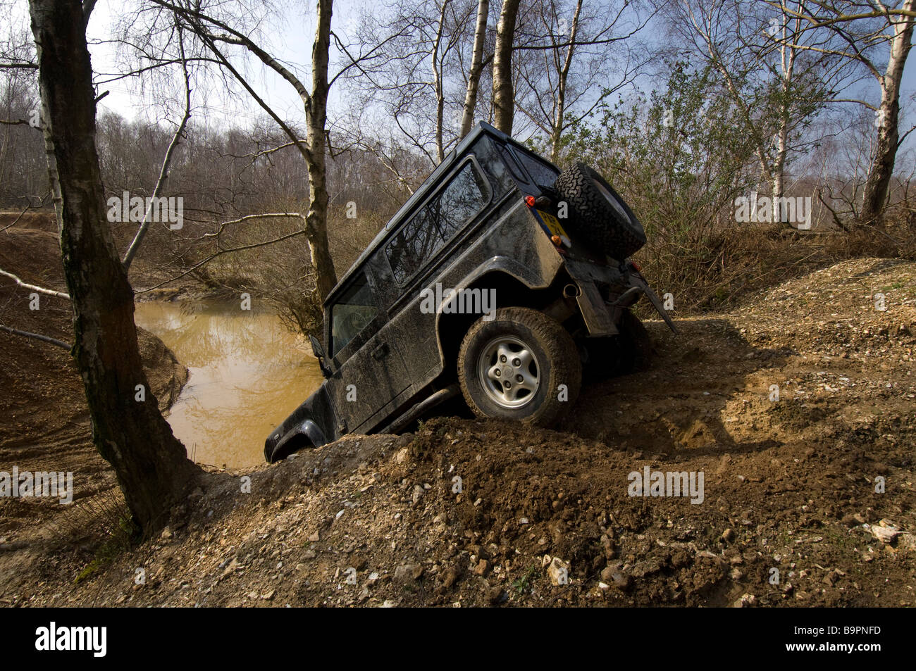 The 2007 design Land Rover Defender 90 creeps down a steep bank to a pond in Slindon West Sussex UK during an Off Road exercise. Stock Photo