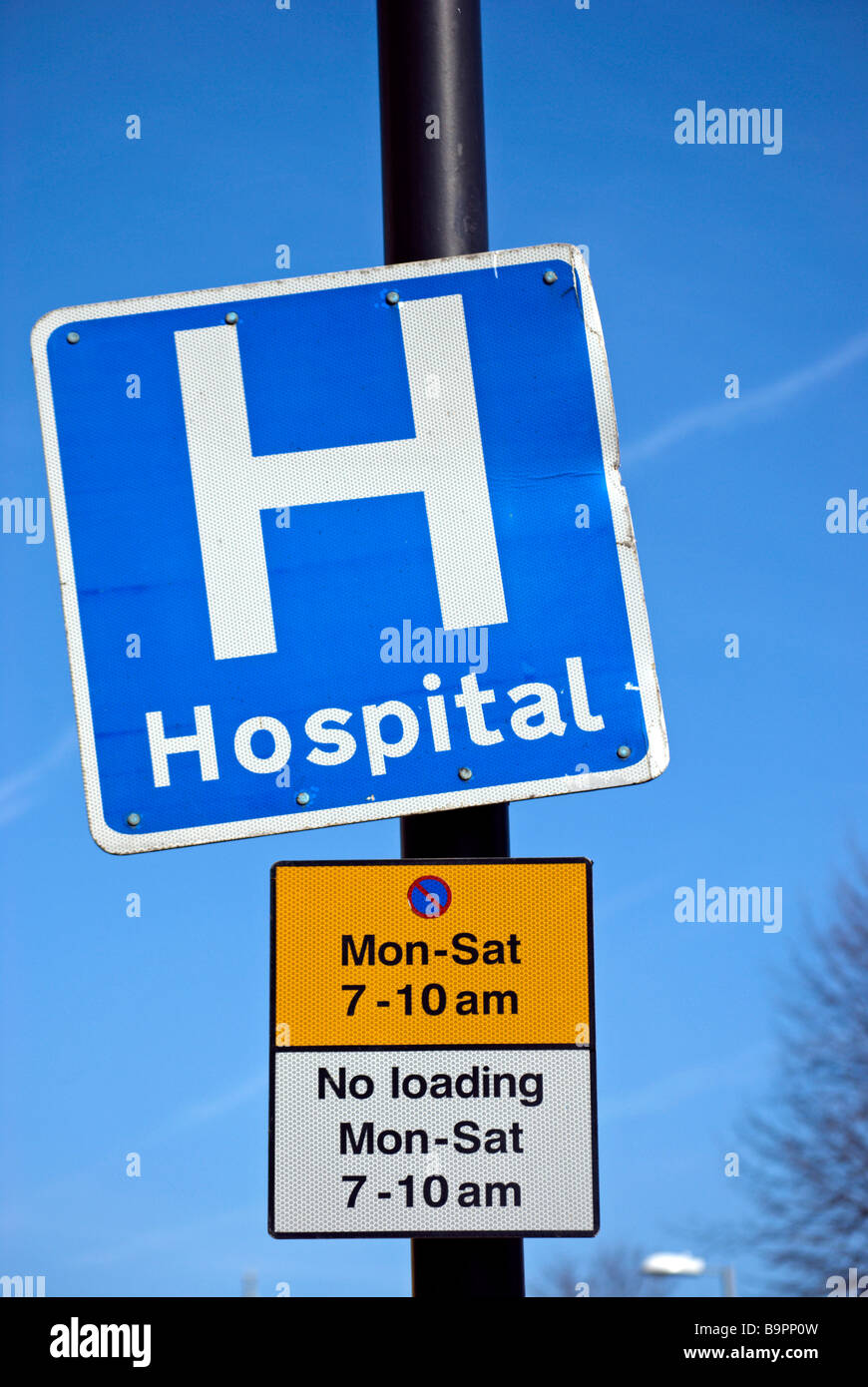 blue and white hospital sign and signs showing parking restrictions, in surbiton, surrey, england Stock Photo