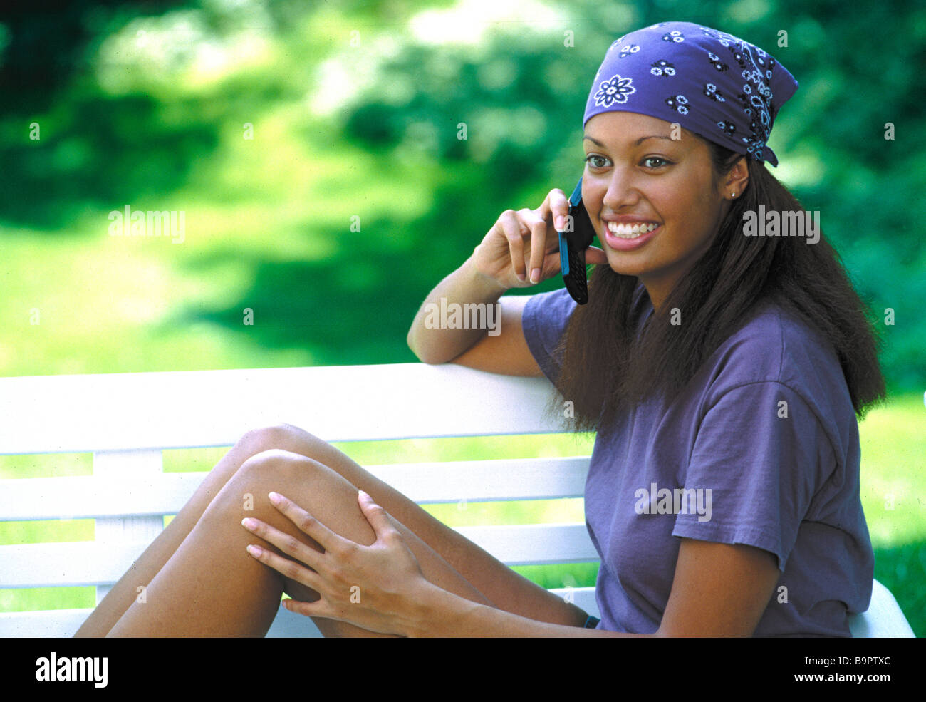 African-American woman sitting on bench talking on cell phone. Stock Photo