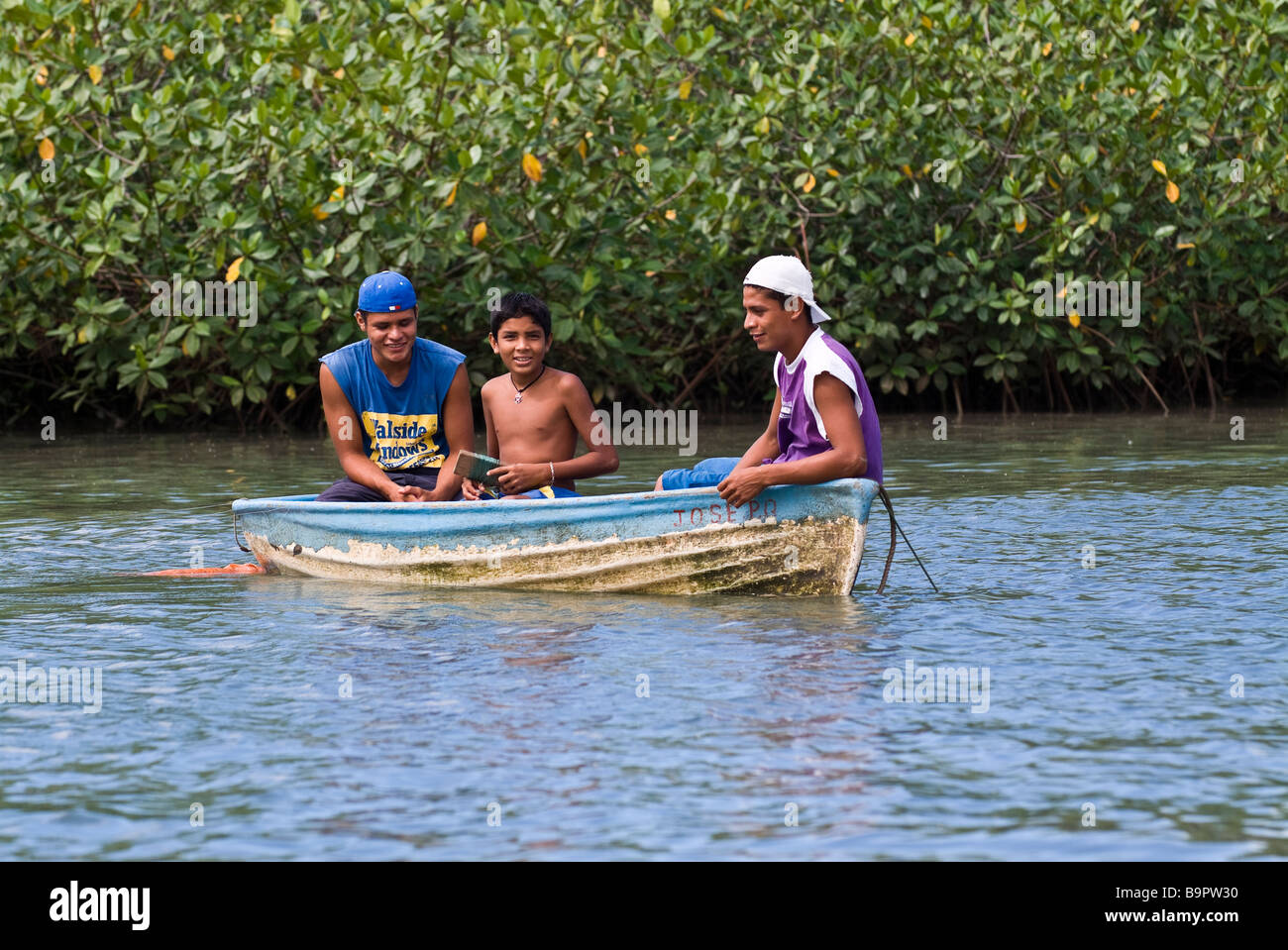 Three boys in small fishing boat, Manuel Antonio National Park, Costa