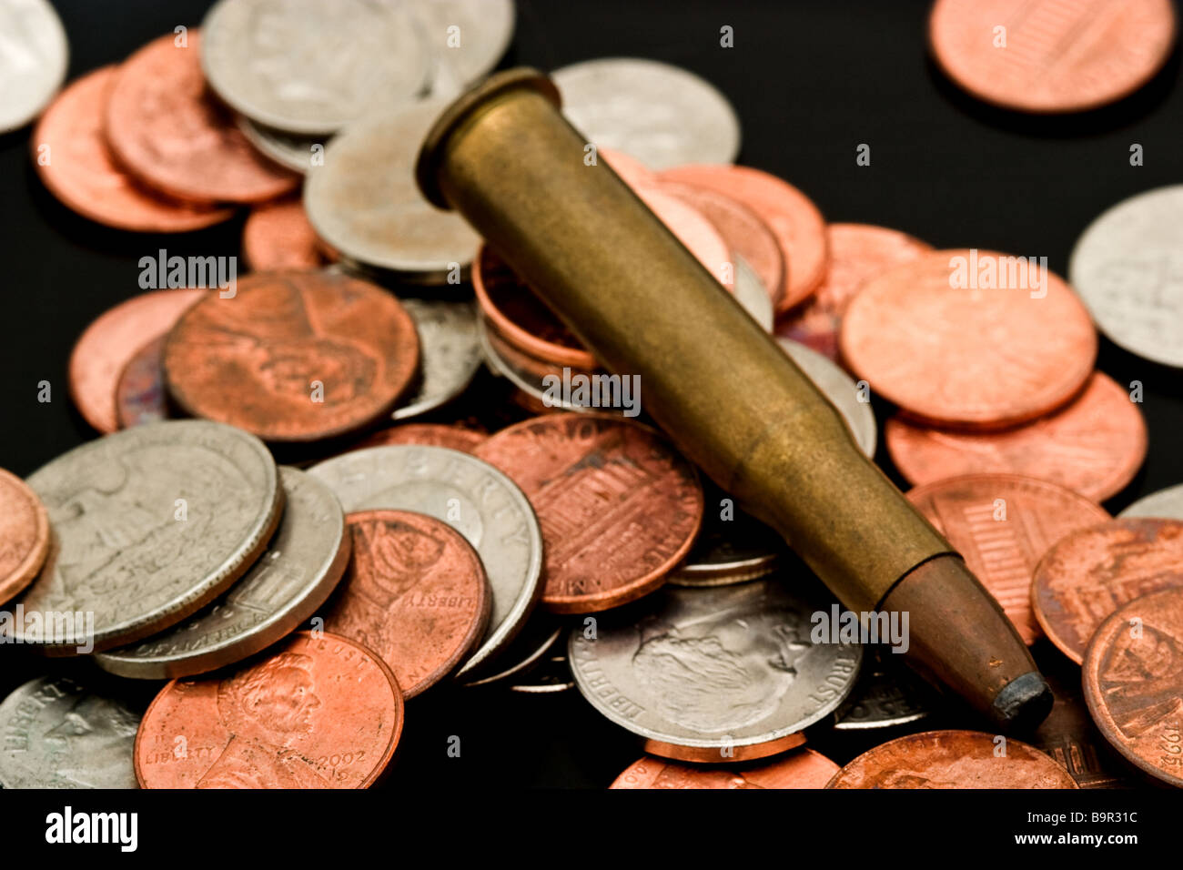 Large caliber bullet in a pile of American coins Stock Photo