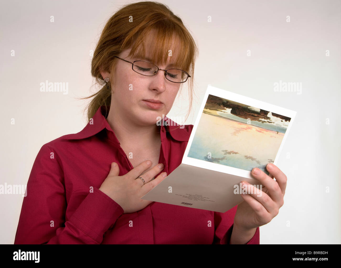 A woman reading a card that has conveyed some news that has made her sad or emotional Stock Photo