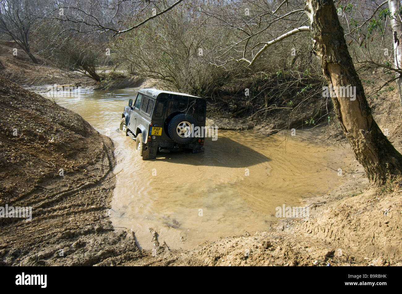 Back view of Land Rover negotiating a steep flooded road. Stock Photo