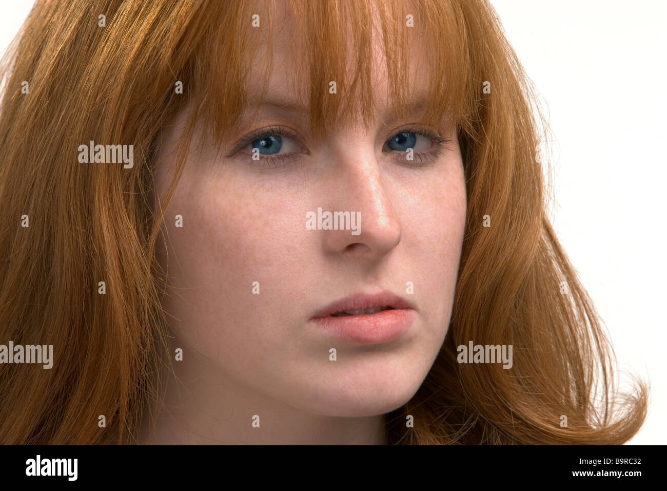 Close up of a red headed woman with a smoldering mean look in her blue eyes Stock Photo