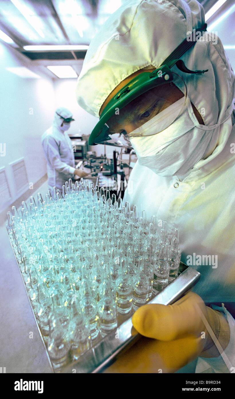Lab technician wearing sterile suit holding tray of medicine ampules in