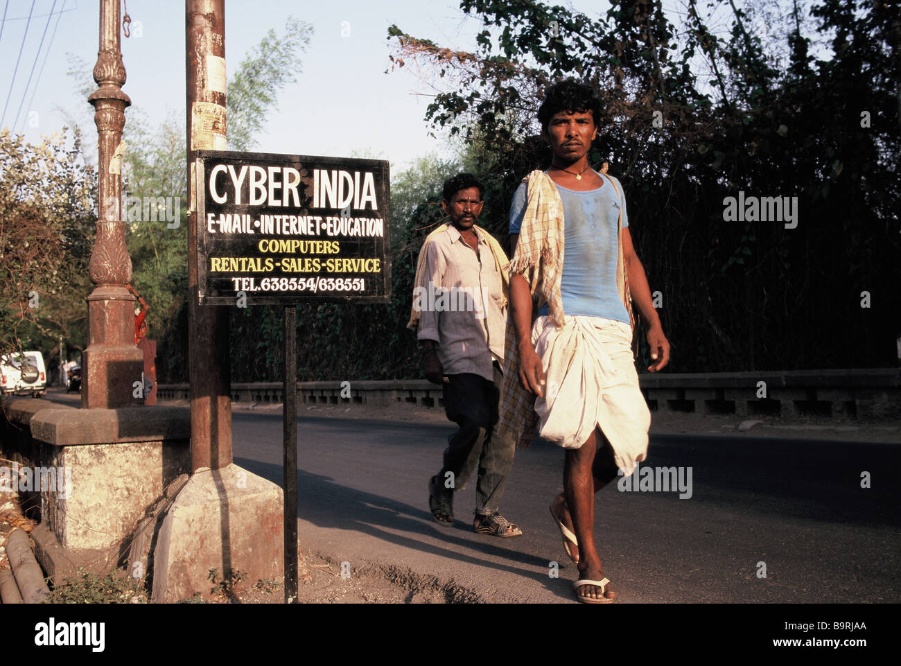 2 men walking past a sign advertising an internet cafe in  Pune, India Stock Photo