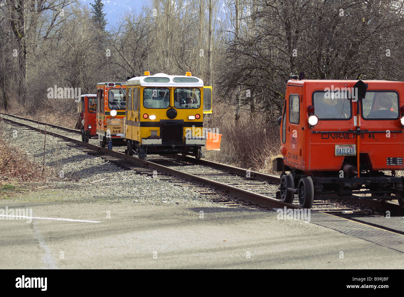 A group of different railcars driving down the railroad tracks in the Snoqualmie Valley preparing for a railroad crossing. Stock Photo