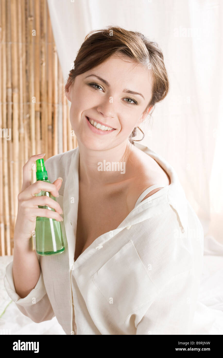 woman using body spray in bedroom Stock Photo