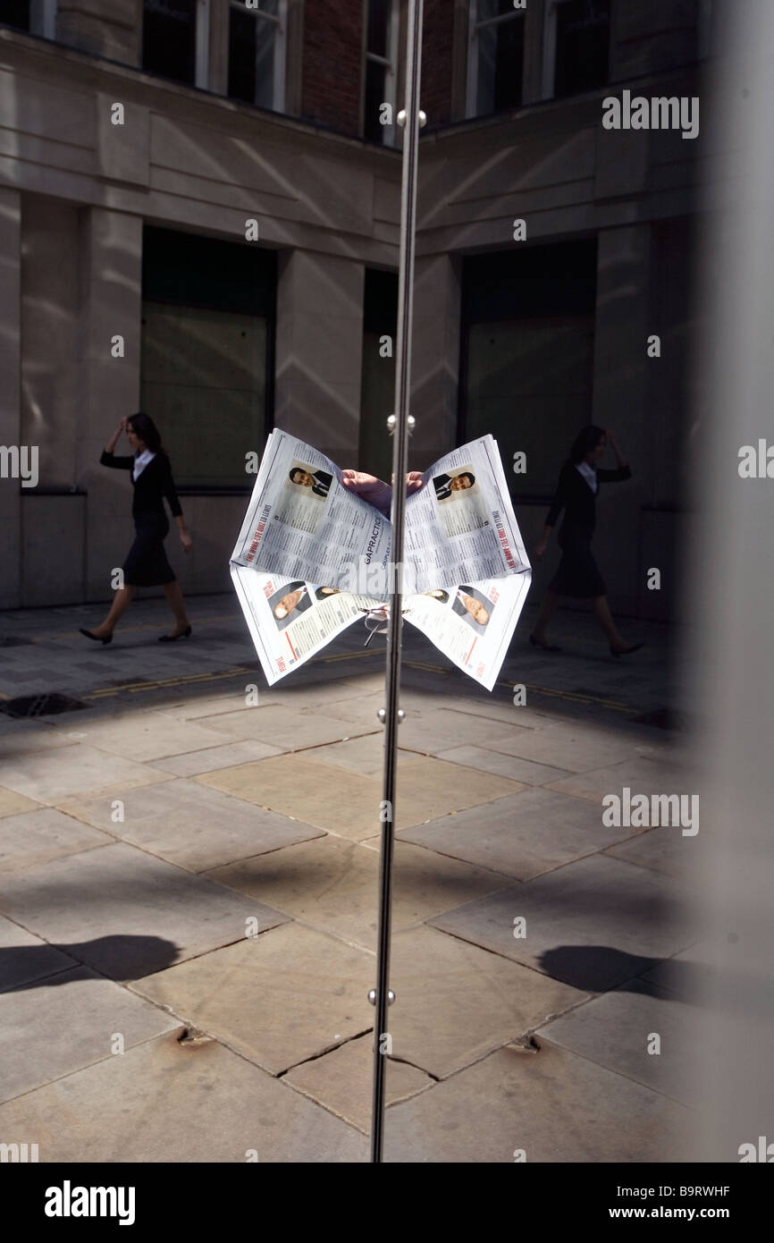 a newspaper being read in a window reflection in fleet street london Stock Photo
