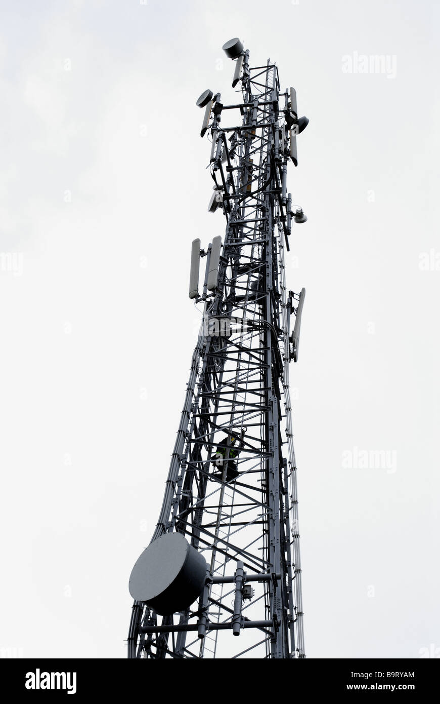 Communication tower with technician at work on a rainy day Stock Photo