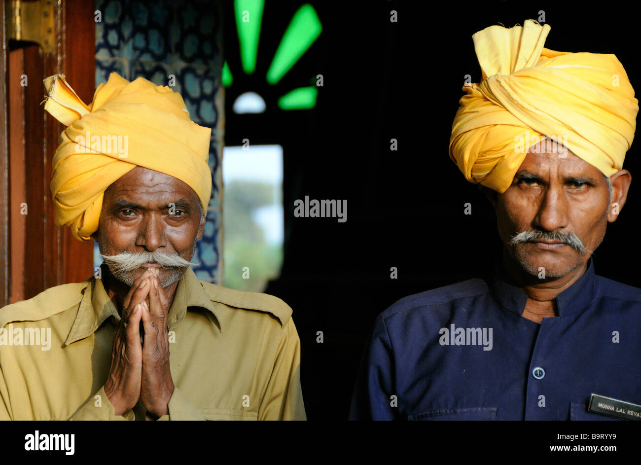 Hotel staff in orange turbans bid farewell to guests Stock Photo