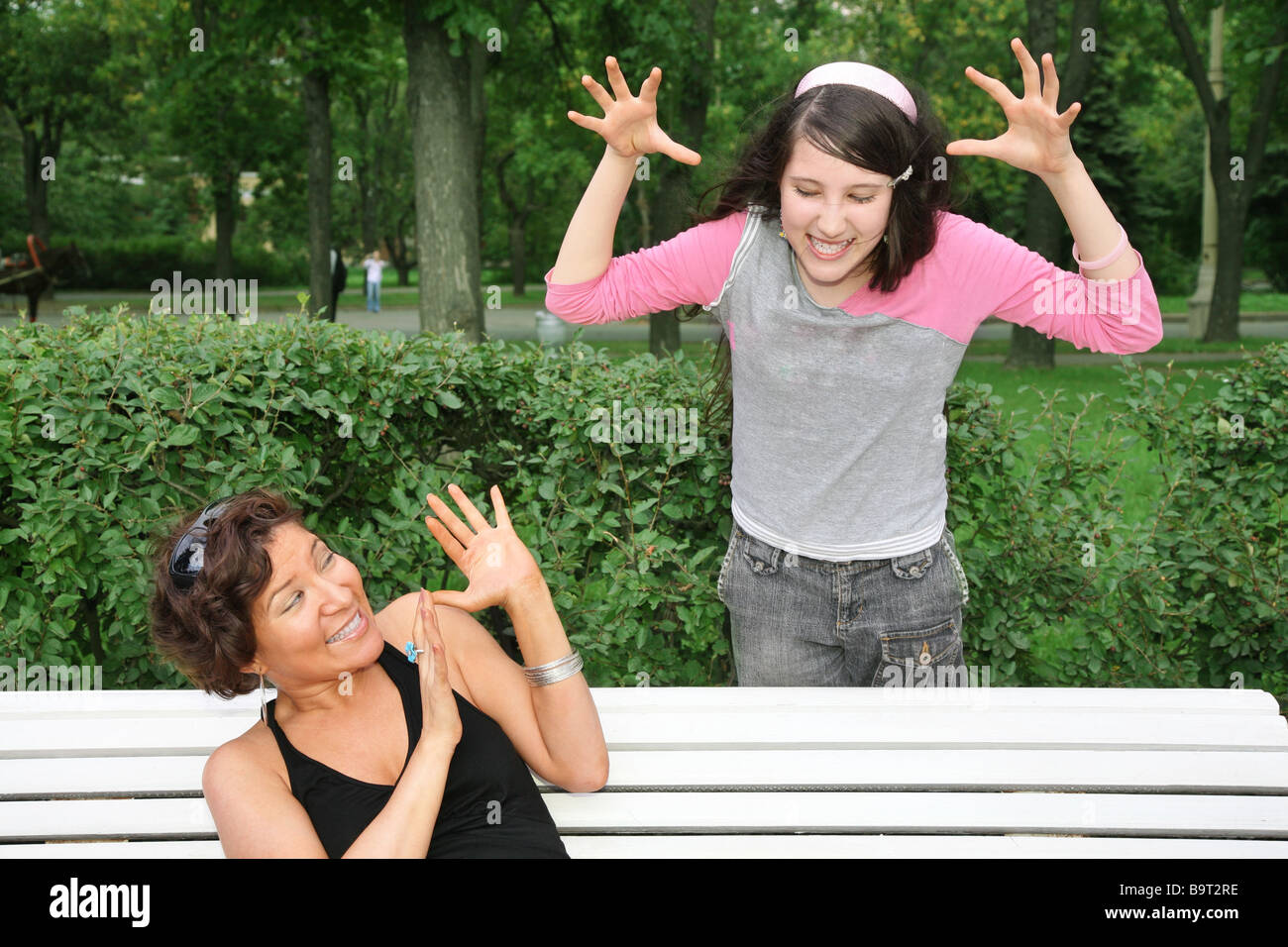 mother sits on the bench, daughter stands near Stock Photo
