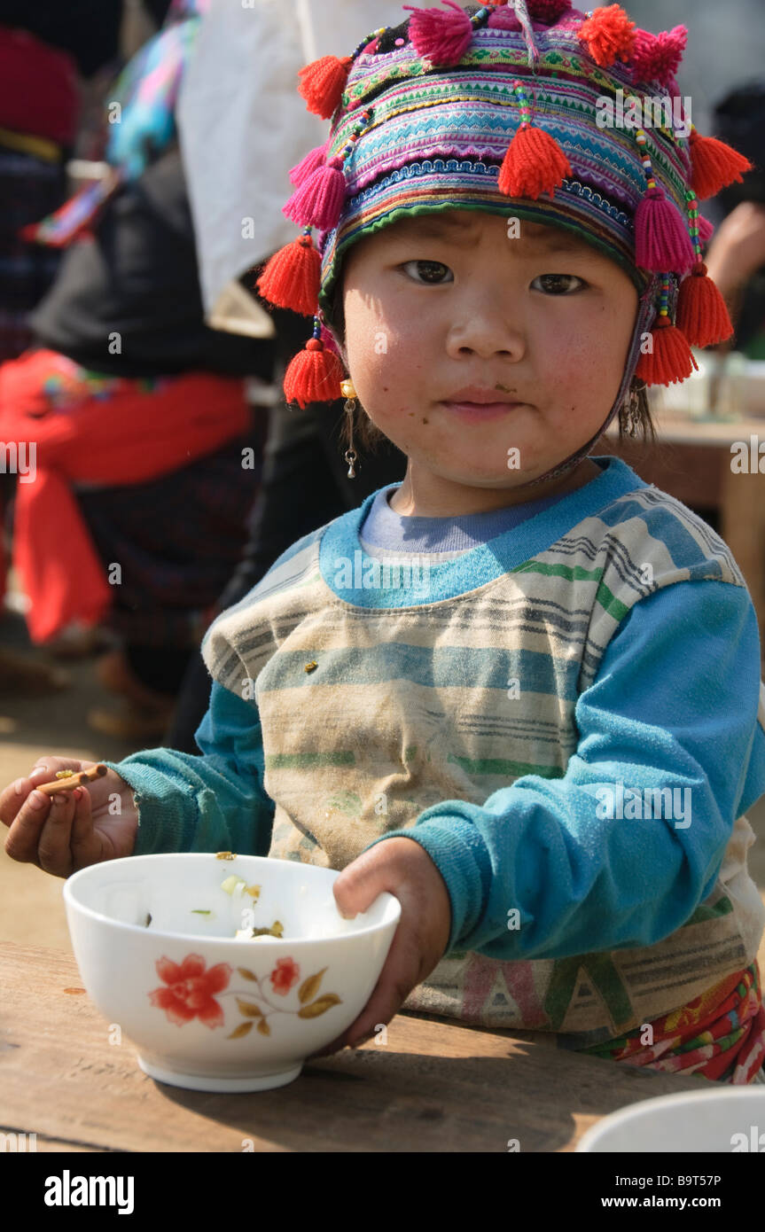 Hmong boy stuffing his face with noodles at market in Tam Duong near Sapa Vietnam Stock Photo