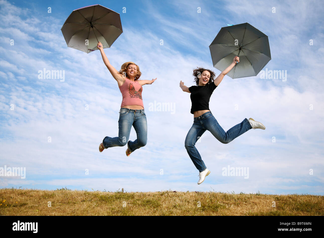 two young women jump with the umbrellas Stock Photo - Alamy