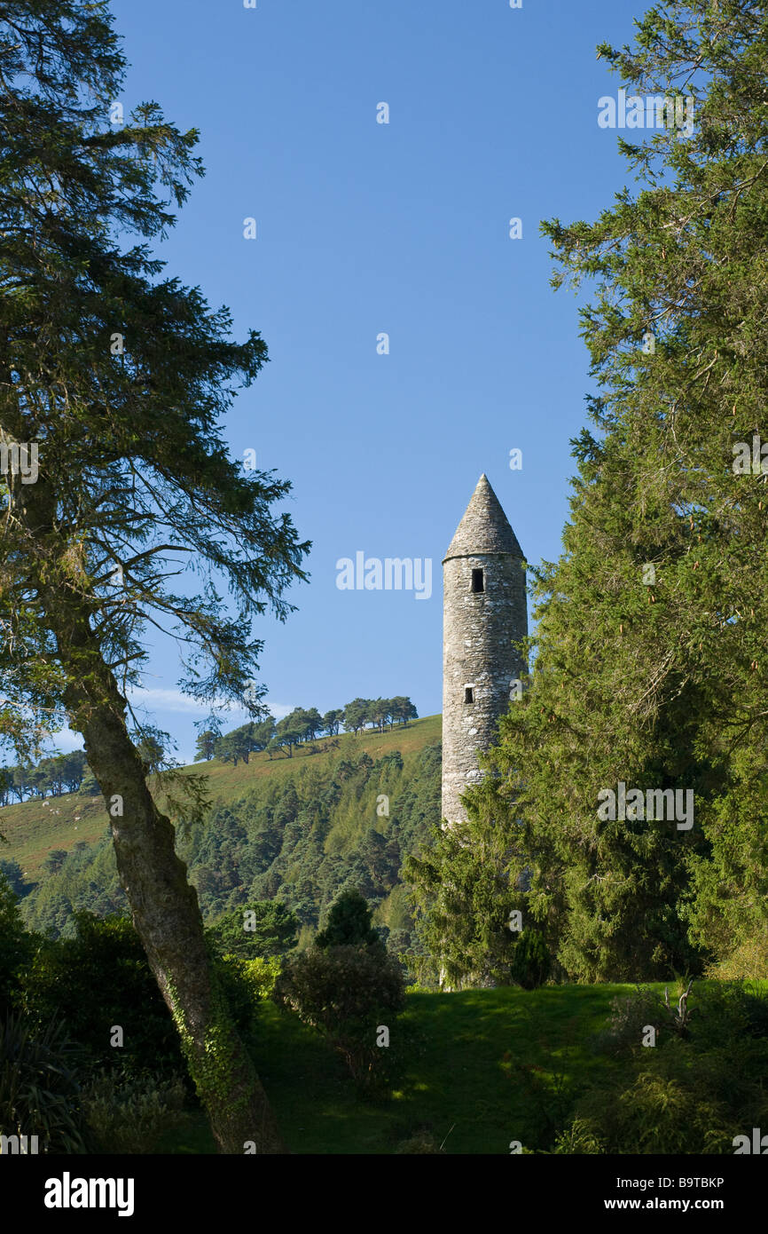 High Round Tower at Glendalough in the trees. Surrounded by lush forests the quiet spaces at this retreat must have been serene. Stock Photo