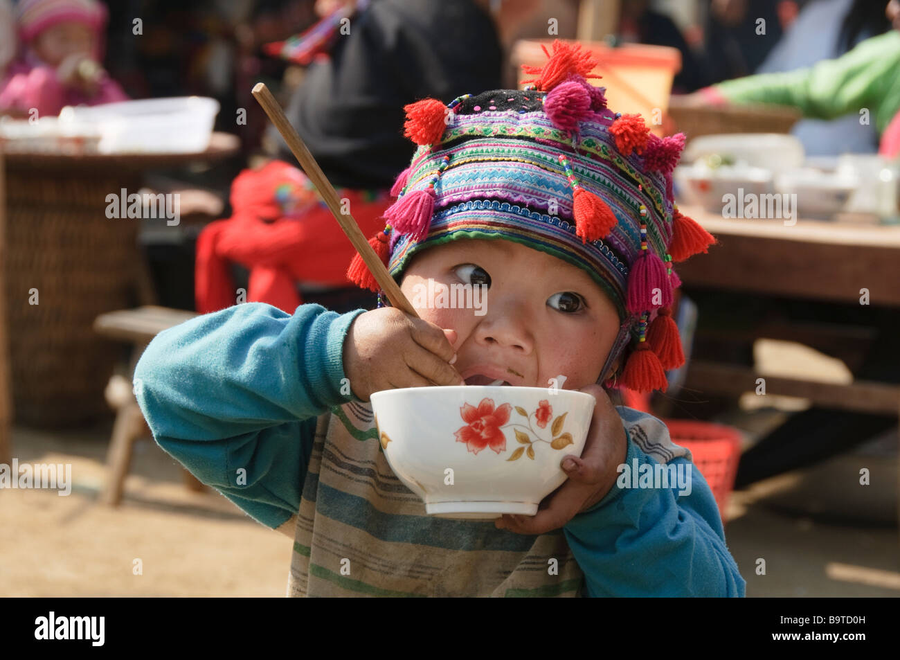 Hmong boy stuffing his face with noodles at market in Tam Duong near Sapa Vietnam Stock Photo