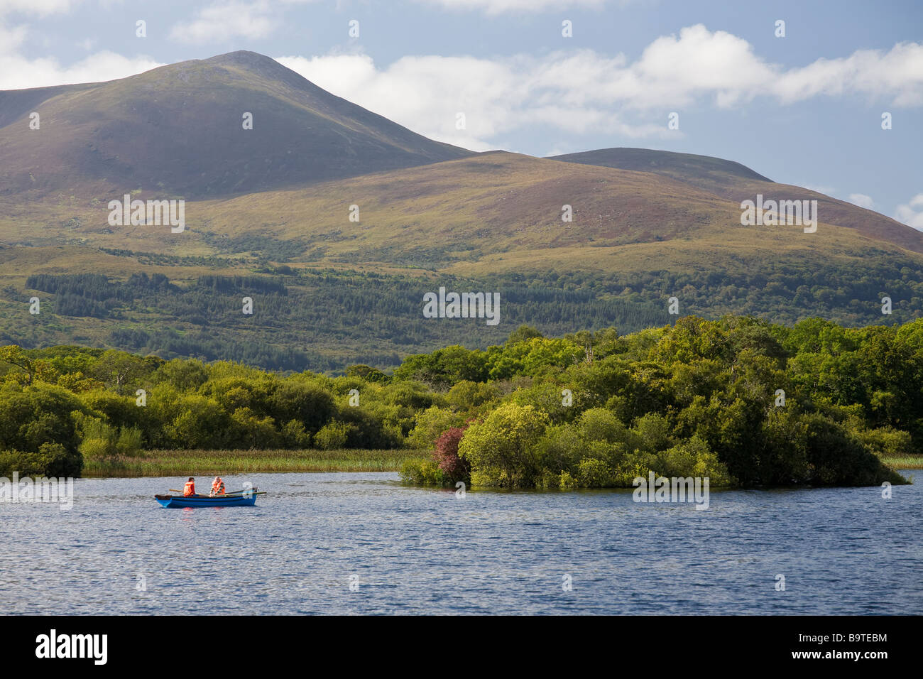 Punt on Killarney Lake. A couple rows out across Killarney lake with the famous mountains in the background. Stock Photo