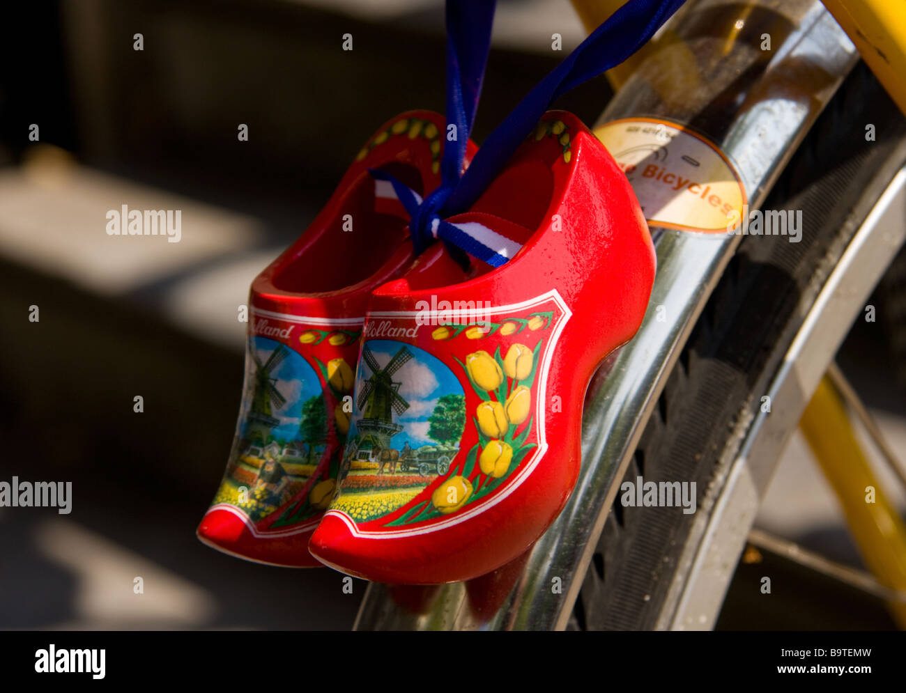 a pair of colourful dutch souvenir clogs tied to a bicycle mudguard Stock Photo