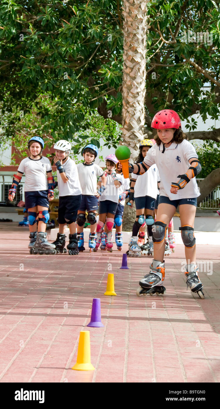 Teams of junior school pupils compete in slalom rollerblade course with ball and cup balancing competition Stock Photo