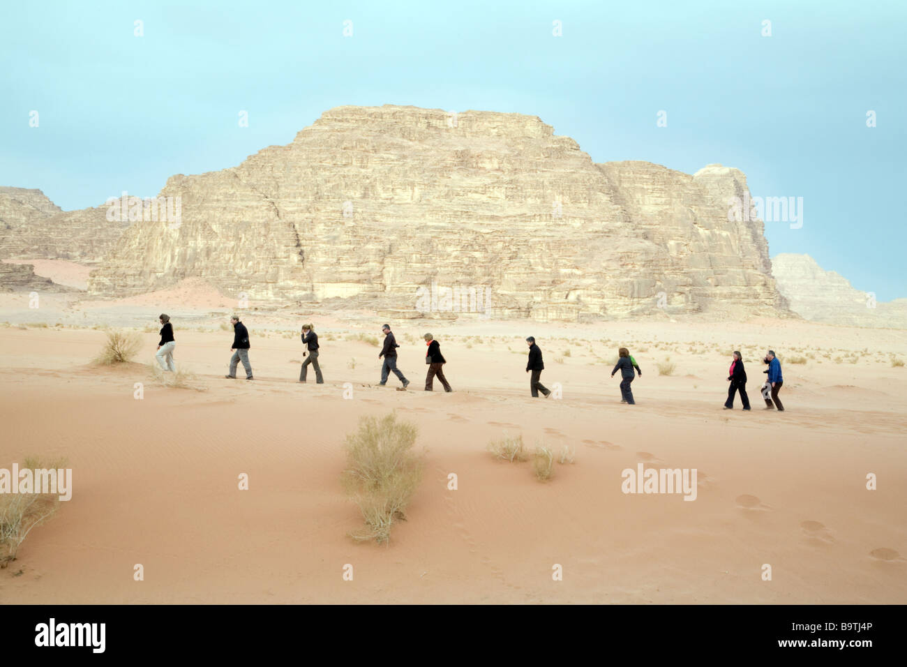 Jordan tourists; People walking in a line at sunrise in the desert, Wadi Rum, Jordan, Middle East Stock Photo