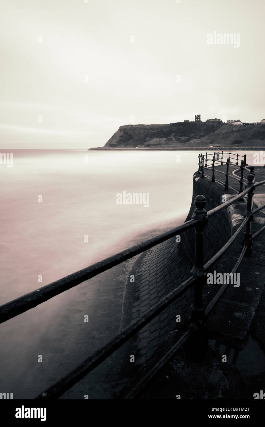 A long exposure has transformed the wild seas into a picture of peaceful silence, with Scarborough Castle on the headland. Stock Photo