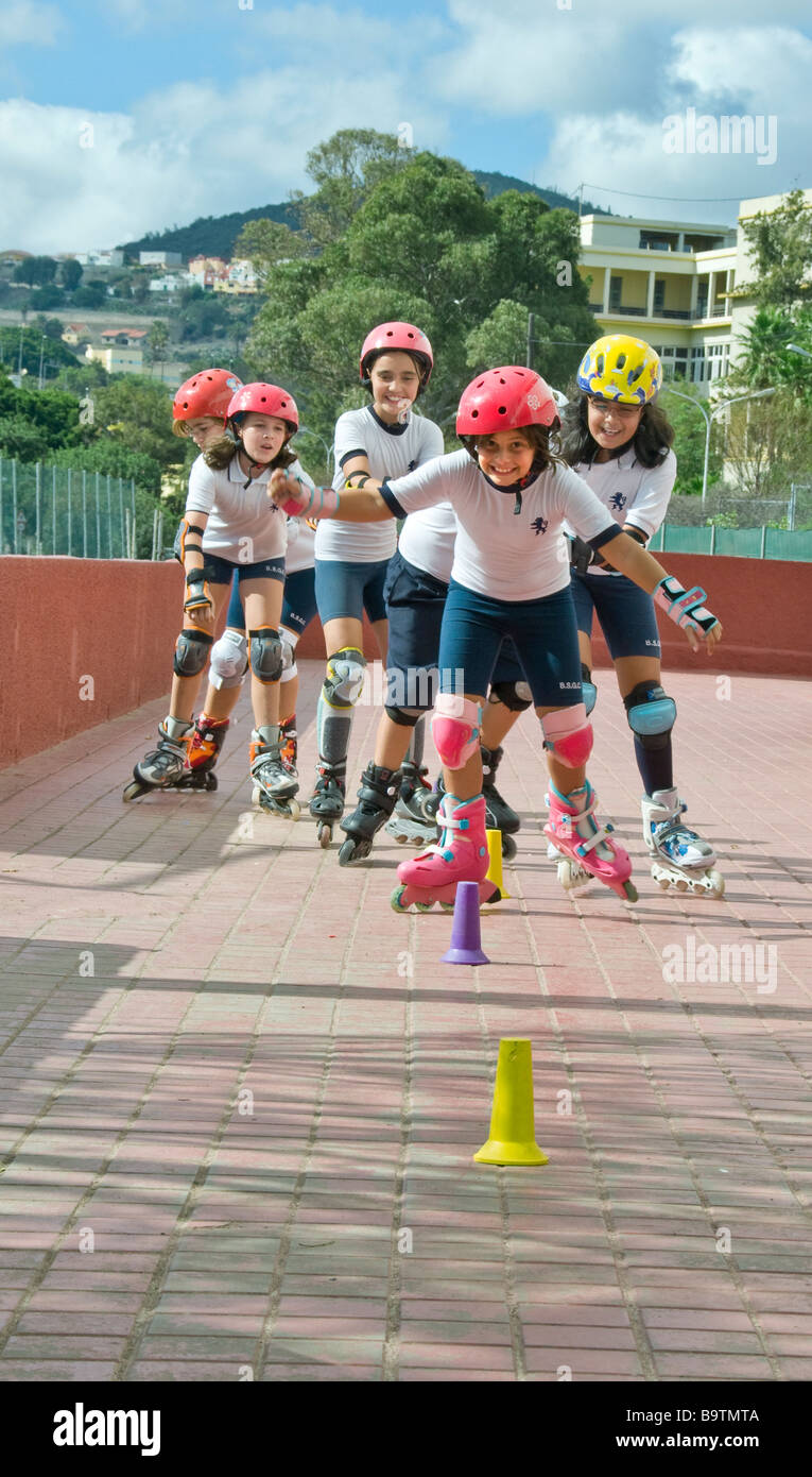 Teams of junior school girl pupils compete in slalom rollerblade  competition wearing full safety sports equipment Stock Photo